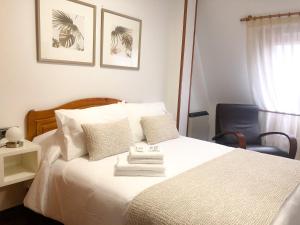 a bedroom with a white bed and a chair at Pensión As Burgas in Caldas de Reis