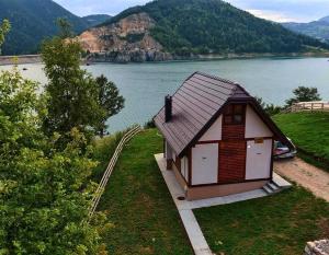 une petite maison à côté d'une masse d'eau dans l'établissement Zoranovi konaci, à Jevtići