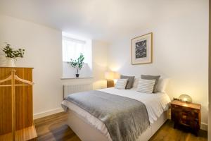 Concorde House Luxury Apartments - Chester في تشيستر: غرفة نوم بسرير وملاءات بيضاء ونافذة