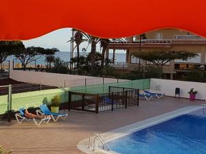 a view of a swimming pool with chairs and a building at PLAYA LAS VISTAS LOFT in Los Cristianos