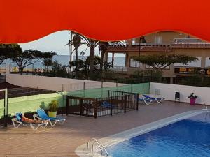 a view of a swimming pool with chairs and a building at PLAYA LAS VISTAS LOFT in Los Cristianos