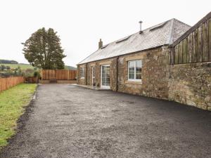 an old stone building with a driveway next to it at The Old Byre in Jedburgh