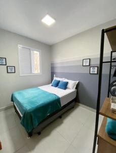 a bedroom with a bed with blue pillows at Jardim das Palmeiras II Home Resort in Ubatuba