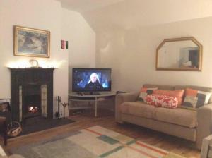 a living room with a couch and a tv and a fireplace at Quaint and Quirky Cottage in Port Ellen in Port Ellen