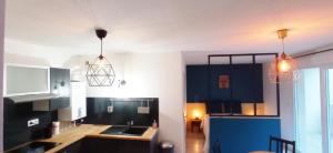 una cocina con armarios azules y dos luces colgantes en Brit's Studio, en Talange
