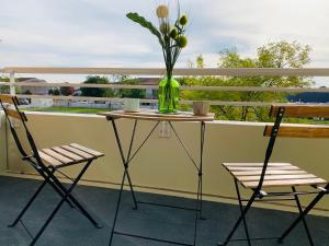 un jarrón de flores sobre una mesa en un balcón en Un confort chaleureux au Rendez-vous en Roques Sur Garonne