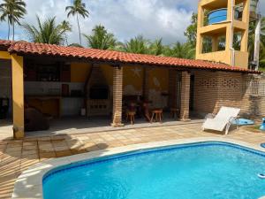 a swimming pool in front of a house at Vila Japaraiso-Casa Amarela Próxima ao mar in Japaratinga