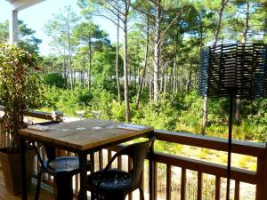 a table on a deck with a view of the woods at Domaine du Ferret Restaurant & Spa in Cap-Ferret