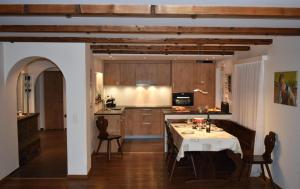 een keuken met een tafel en stoelen en een keuken met houten kasten bij Helvetia (388 Sr) 2. Stock in Lenzerheide