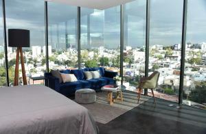 a bedroom with a blue couch in front of a large window at Suites BQ in Guadalajara