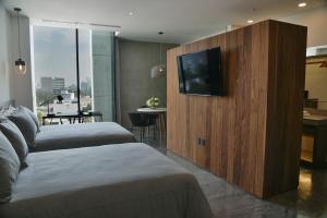 um quarto de hotel com duas camas e uma televisão de ecrã plano em Suites BQ em Guadalajara