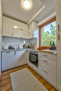 Apartment Grey Mountain في زلاتيبور: مطبخ مع دواليب بيضاء ونافذة