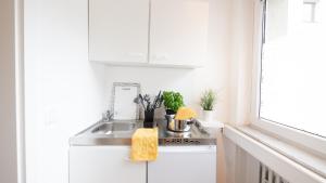 a kitchen with white cabinets and a sink at Relax Aachener Boardinghouse Appartements Premium 1 in Aachen