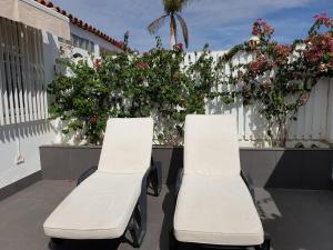 dwa białe krzesła siedzące na balkonie z kwiatami w obiekcie Espacioso Bungalow 2 dormitorios en Maspalomas w mieście Maspalomas