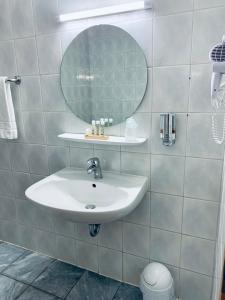 a white bathroom with a sink and a mirror at DUA Hotel in Wennigsen