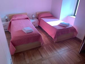 Habitación con 2 camas, colchas rosas y suelo de madera. en B&B L’antico Rudere en Cosenza