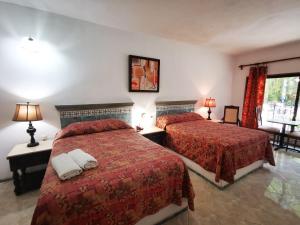 a hotel room with two beds with red sheets at Hotel Doralba Inn in Mérida