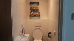 a bathroom with a toilet and a sink and signs at 2 persoons zon en zee in Westkapelle +8 photos