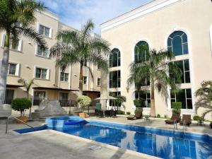 a swimming pool in front of a building with palm trees at Holiday Inn Reynosa Zona Dorada by IHG in Reynosa