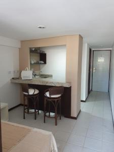 a kitchen with two chairs and a counter with a sink at Pipas Bay - FLAT BEIRA MAR in Pipa