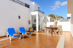 un patio con sillas azules y una mesa en el suelo de baldosa en Luis iii, en Puerto del Carmen