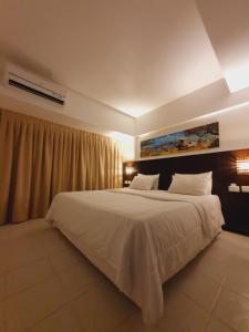 een slaapkamer met een groot bed met witte lakens bij Pipas Bay - FLAT BEIRA MAR in Pipa