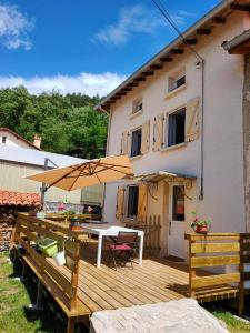 a wooden deck with a table and an umbrella at Les Petites Poussières in Bas-en-Basset