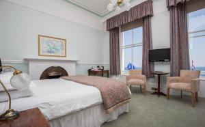 a bedroom with a bed and a fireplace and a tv at The Queens Hotel in Penzance