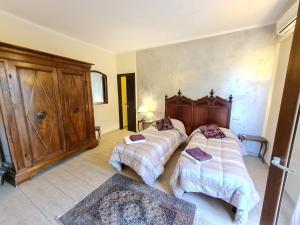 サルザーナにあるB&B Al Calcandolaのベッドルーム1室(ベッド2台、木製ヘッドボード付)