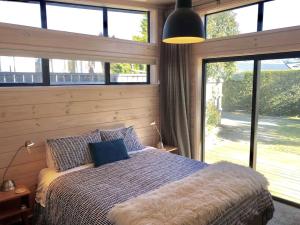 a bedroom with a bed and a large window at Modern Kowhai Cottage in Wanaka