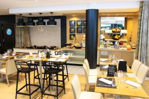 a restaurant with tables and chairs and a kitchen at Aiden by Best Western at Paris Roissy CDG in Roissy-en-France