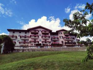 a large white building with red flowers on balconies at Hotel Spera in Strigno