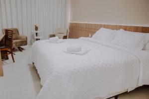 uma grande cama branca num quarto com uma cadeira em Confort Fronteira Hotel em Santana do Livramento
