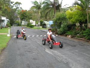 
a man riding on the back of a red and white scooter at Anchorage Holiday Park in Iluka
