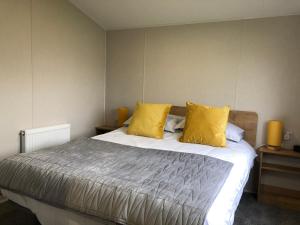 a bedroom with a large bed with yellow pillows at Whitley bay 4 berth Luxury Caravan in Newcastle upon Tyne