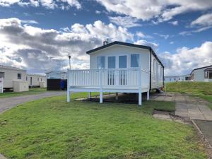 una pequeña casa sentada en la cima de un campo de hierba en Whitley bay 4 berth Luxury Caravan, en Newcastle