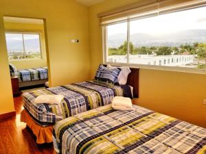 two beds in a room with a large window at Hotel Casa Sayu in Tumbaco