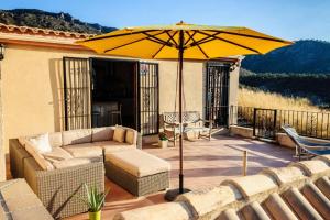 eine Terrasse mit einem Sonnenschirm, einem Sofa und Stühlen in der Unterkunft Casa Buena Vista - Campo de Ricote in Cuesta Alta