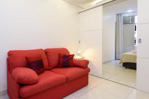 Sofá rojo en una habitación con dormitorio en Refúgio em Copacabana - Perto da praia - DF219 Z3, en Río de Janeiro