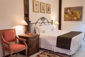 a bedroom with a bed and a chair and a table at Pouso da Torre in Tiradentes