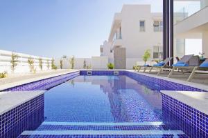 una piscina con piastrelle blu sul lato di un edificio di Villa Medusa a Protaras