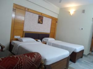 a room with three beds in a room at Hotel PLR Grand in Tirupati