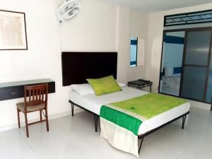 a bedroom with a bed with a chair and a desk at Hotel Morfeo in Tuluá