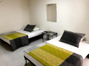 a room with two beds and a mirror on the wall at Hotel Morfeo in Tuluá