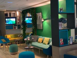 a waiting room with a green couch and chairs at Holiday Inn Paris Montmartre by IHG in Paris