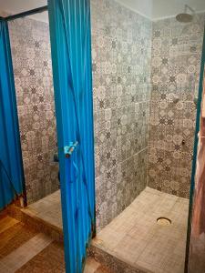 a bathroom with a shower with a blue glass door at Yaxche Centro Hostal y Camping in Bacalar