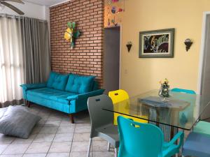 ein Wohnzimmer mit einem blauen Sofa und einem Glastisch in der Unterkunft Guarujá Enseada 8 lugares a meia quadra da praia in Guarujá