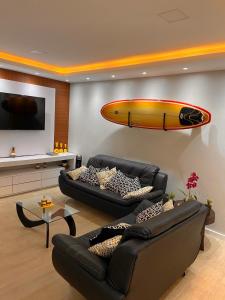 a living room with two couches and a surfboard on the wall at Mirante dos Anjos Suítes in Arraial do Cabo