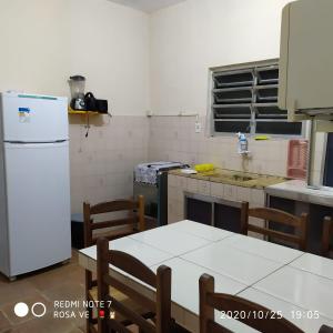 a kitchen with a white refrigerator and a table and chairs at Temporada no Paraíso in Ilha Comprida
