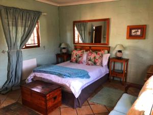 Schlafzimmer mit einem Bett und einem Spiegel in der Unterkunft Natures Rest Lapa in Oudtshoorn